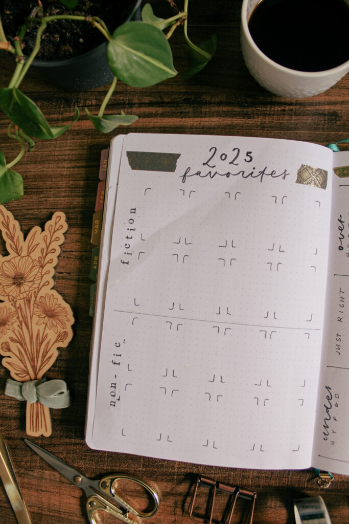 Emily's reading journal is open to a page to track her 2025 Favorite books, divided by fiction and non-fiction books. On the desk surrounding her notebook are various stationery and decorative elements.